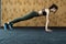 Full-length side view of young beautiful woman in sportswear doing plank at gym