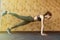 Full-length side view of young beautiful woman in sportswear doing plank at gym