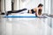 Full-length side view of young beautiful woman in sportswear doing plank while standing in front of window at gym