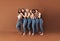 Full length of six smiling women embracing in studio. Females of different ages and body types posing over brown background