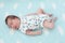 Full length of sleeping Caucasian baby one month old, lying on light blue bedsheet with white clouds