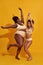 Full length of two excited african american women in beige underwear with different body size jumping, having fun