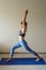 Full length vertical image. Young european woman wearing sport clothes doing workout at home exercising doing yoga home fitness