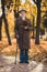 Full length vertical photo of cheery old pensioner grey hair grandpa park walk cane enjoy sunny day hold bunch dry leaf