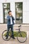 Full length vertical portrait of handsome young man putting helmet on head before going to go ride by bicycle in city