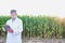 Full length view of crop scientist wearing lab coat while using digital tablet against corn plant growing in field