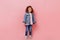Full length view of curly preteen girl in jeans. Studio shot of cute child isolated on pink background