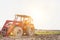 Full length view of tractor in field with yellow lens flare