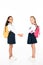 full length view of two cute multicultural schoolgirls holding hands and looking at camera on white background.