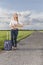 Full length of woman hitching while holding anywhere sign on country road