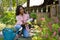 Full length of young african american kneeling while planting flowering plants at garden