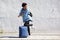 Full length young black female traveler standing with luggage and looking back