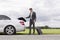 Full length of young businessman unloading luggage from broken down car at countryside