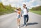 Full length of young couple walking along road, holding hands, catching ride, waiting for car, copy space