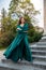 Full length young elegant woman in beautiful green gress standing in stone   stair