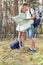 Full length of young hiking couple reading map in woods