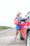 Full length of young woman refueling car on country road