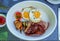 Full meat set of American breakfast with fried eggs, bacon, pork, potato and tomato