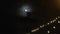 Full moon above a strand of decorative lights on a pier