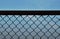 Full moon behind iron wire fence on bright sky in evening