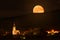 The full moon of hunters, the moon rises over the forest in the mountains. Illuminated church in a small village in the mountains