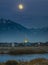 Full moon over homes lake and mountain in Daybreak