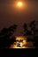 Full moon over ocean beach and mangroves, reflections framed by silhouetted trees