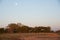 Full moon over public park near row of shade structure pavilion at Grapevine Lake, Texas, US, sandy shoreline with first