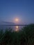 The full moon is reflected in the glare of the river, reeds admire it