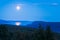 Full moon reflects in water surface of lake deep in Swedish arctic. Night in remote Lapland wilderness. Tjaktjajavrre