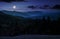 Full moon rise above forested mountain at night