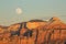 The full moon rises over the mesas of Southern Utah as the evening light paints the cliffs a warm gold