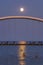 Full moon rising behind the Humber Bay Arch Bridge reflecting in Lake Ontario