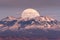 Full moon rising behind La Sal Mountains in Canyonlands National Park during sunset