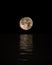 Full Moon Rising Over Calm Sea with reflection on water, Vertical