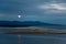 Full moon rising over lake & sea landscape at dusk