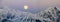 Full moon rising over a winter mountain landscape