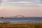 Full moon rising through a soft pastel colored sky above a long steel tied arch bridge