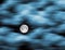 A full moon is seen as fast moving clouds