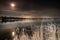 Full moon shines over autumn lake with reflection at calm surface, dried yellow grass at the coast line, typical scandinavian