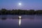 the full moon is shining on a beautiful lake at dusk