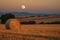 full moon shining over the harvest moon, casting its light on the fields