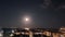 full moonrise over the sea in the clouds over the seaside city. timelapse