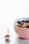 Full muesli bowl on a white table with blueberry. Healthy breakfast cereals with milk, seed, fruit. Oat flakes