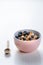 Full muesli bowl on a white table with blueberry. Healthy breakfast cereals with milk, seed, fruit. Oat flakes