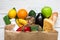 Full paper bag of different healthy vegetarian food on white wooden background