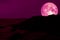 full pink moon back silhouette rock mountain on coast