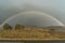 Full rainbow against stormy grey sky on the background