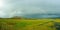 A full rainbow over rural green farmland landscape showing wet rainy weather