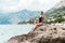 Full relaxation. woman in body swimsuit sitting on a rock at seaside with mountains in background. Croatia travel